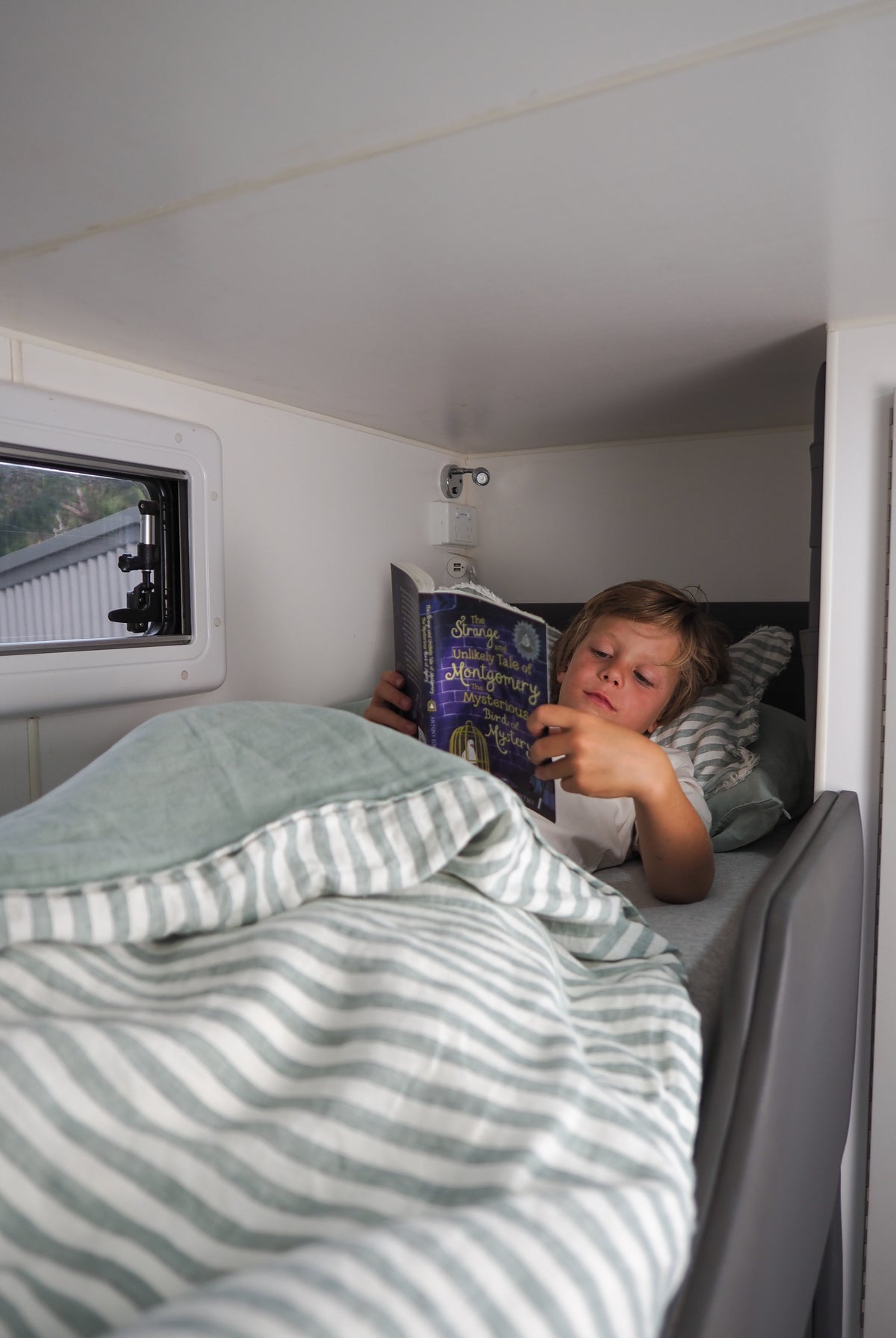 Boy reading book in bunk