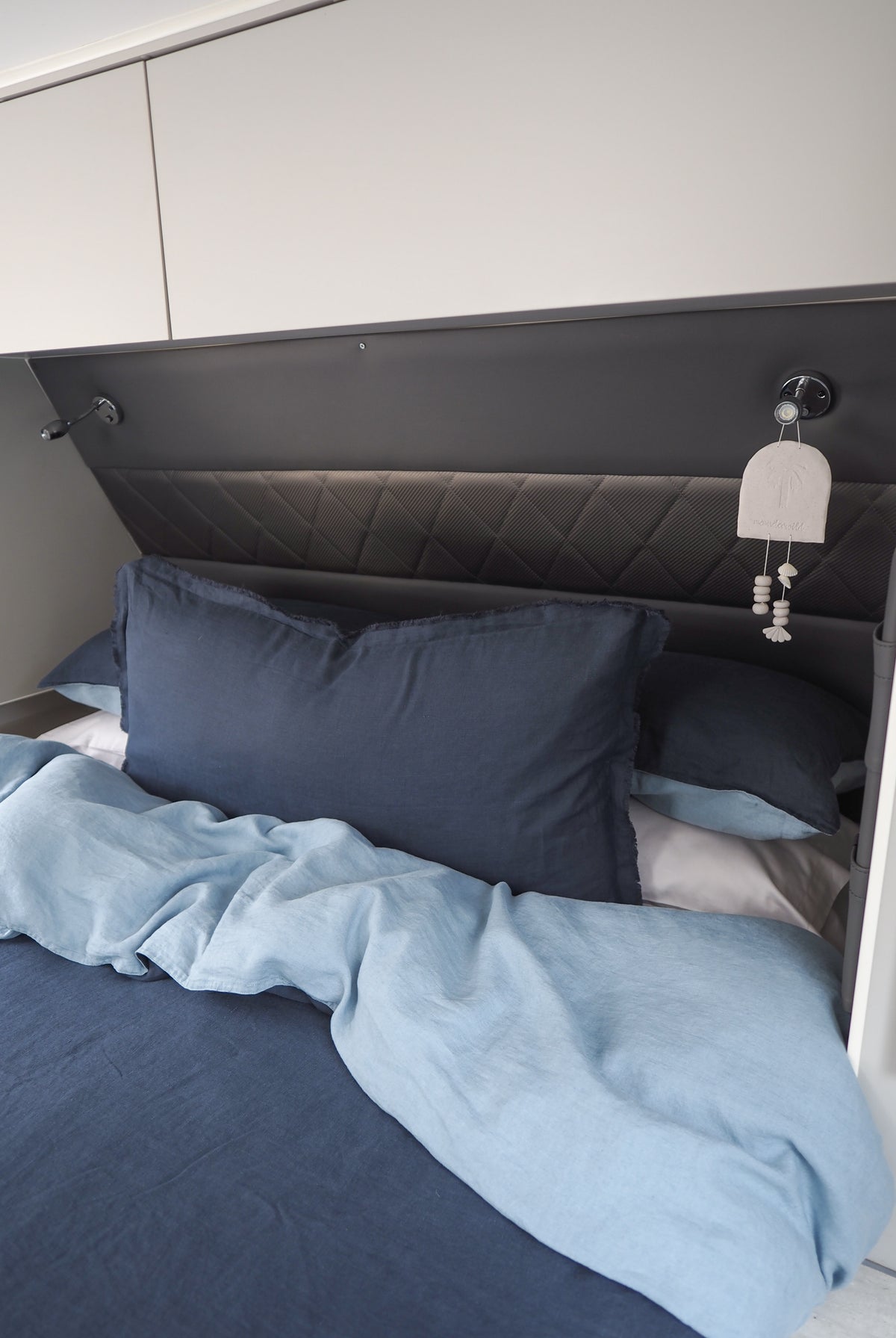 A quilt cover and pillowcase set in navy blue color, displayed on a caravan bed.