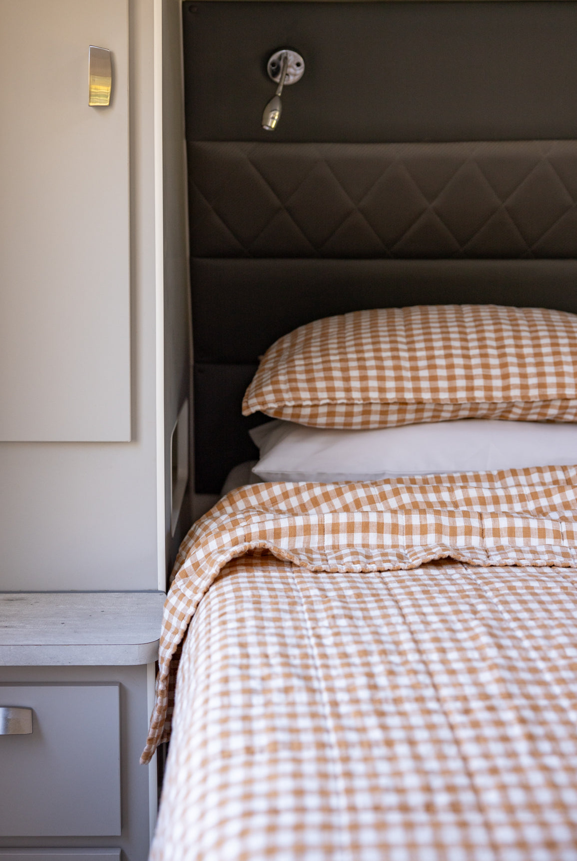 Close up of caravan bed with copper dawn coverlet