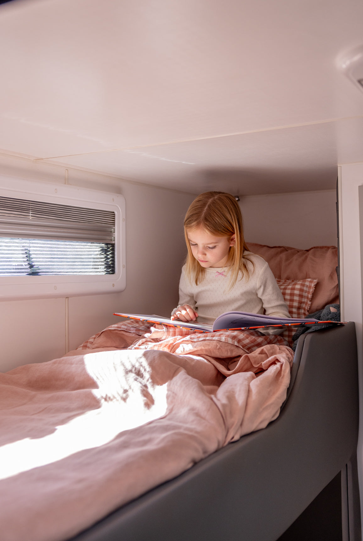 Little Wild Bunk Set in Pink Salt, dusty pink and check European flax linen, on a caravan bunk with little girl reading