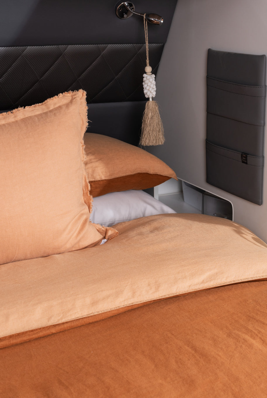 A quilt cover in peach and rust displayed on a caravan bed