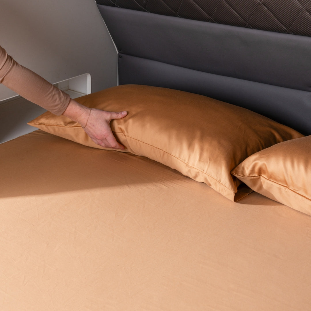 Hand placing a rust pillow on a caravan bed