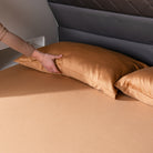Hand placing a rust pillow on a caravan bed