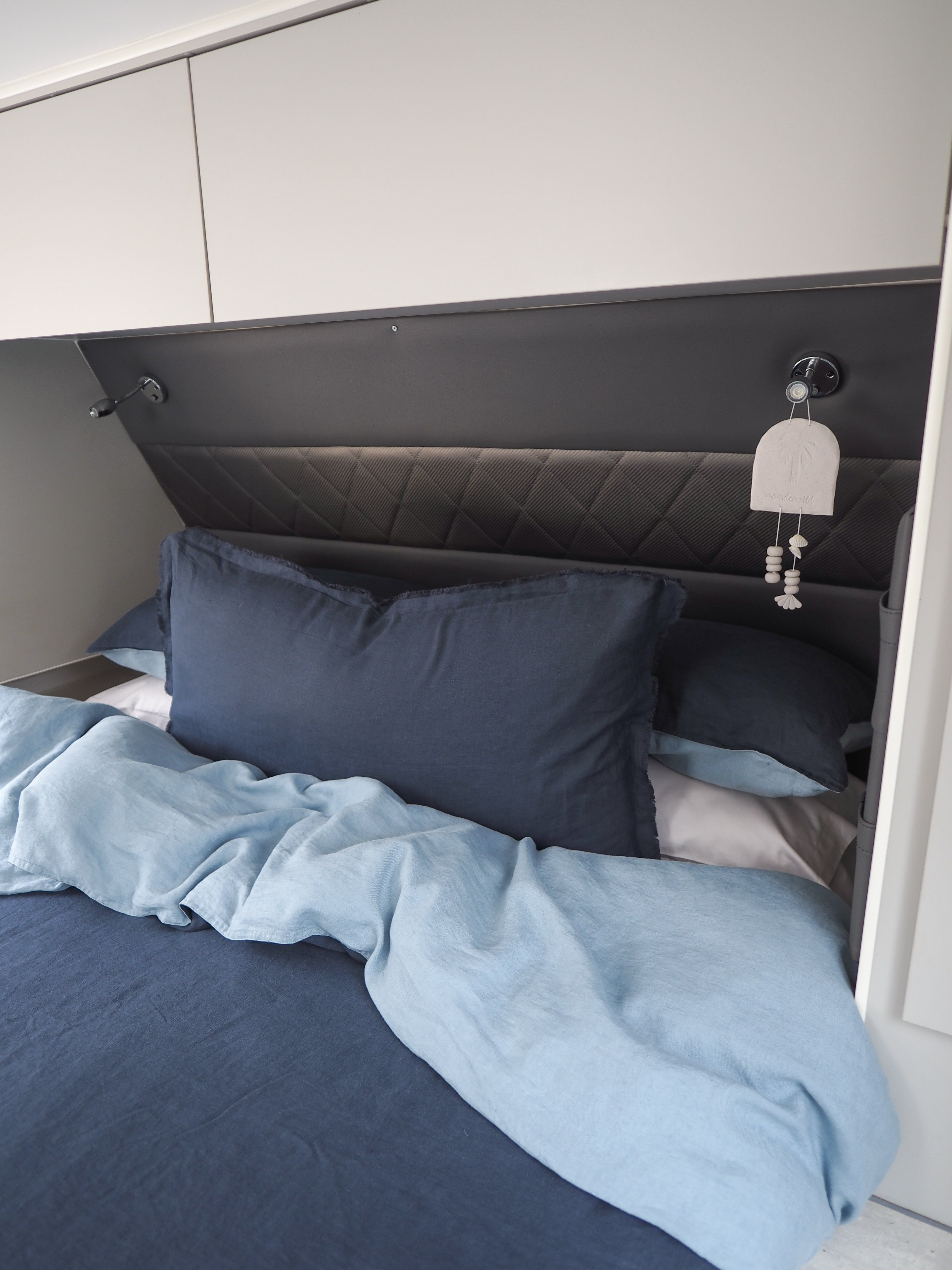 A quilt cover and pillowcase set in navy blue color, displayed on a caravan bed.