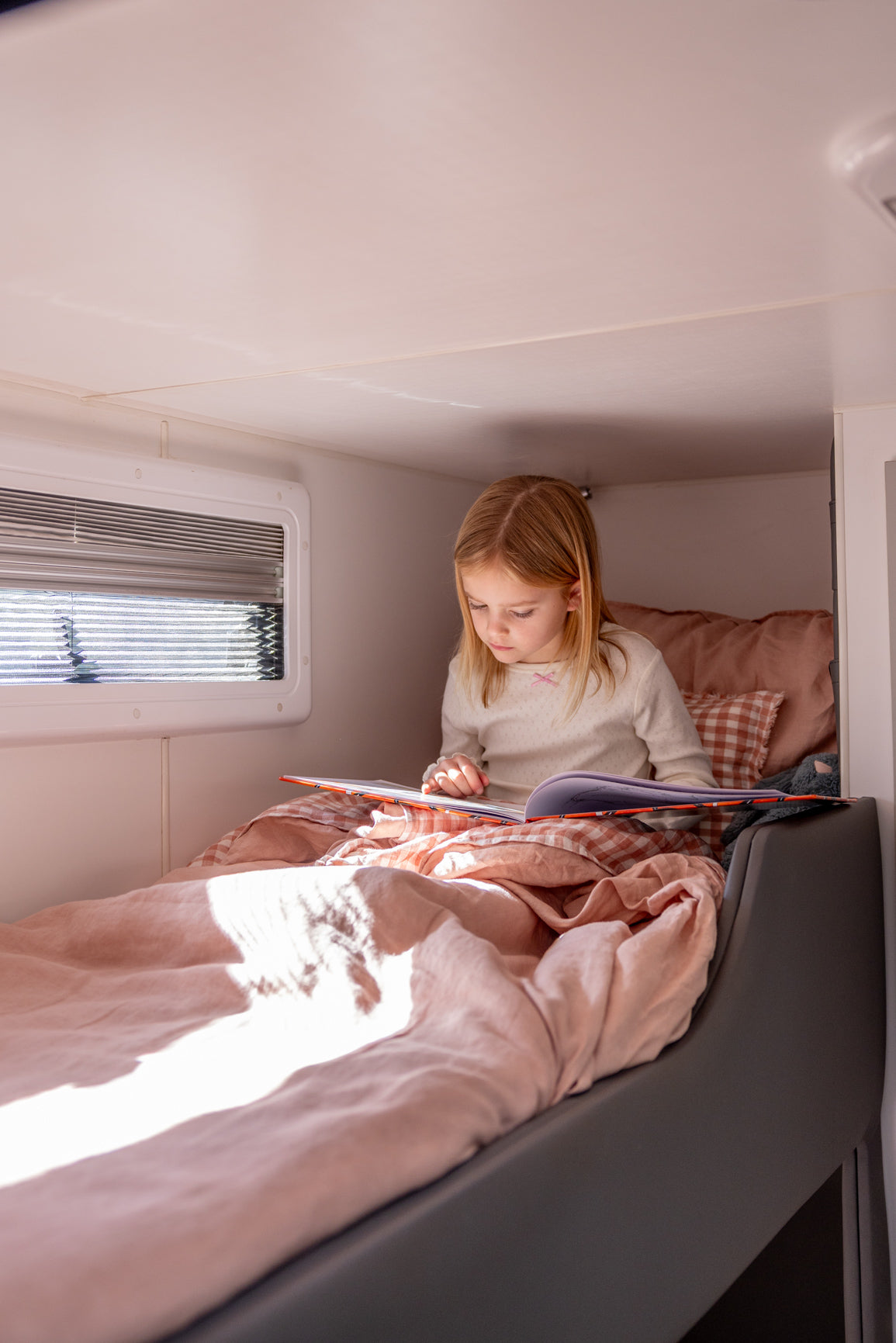 Little Wild Bunk Set in Pink Salt, dusty pink and check European flax linen, on a caravan bunk with little girl reading