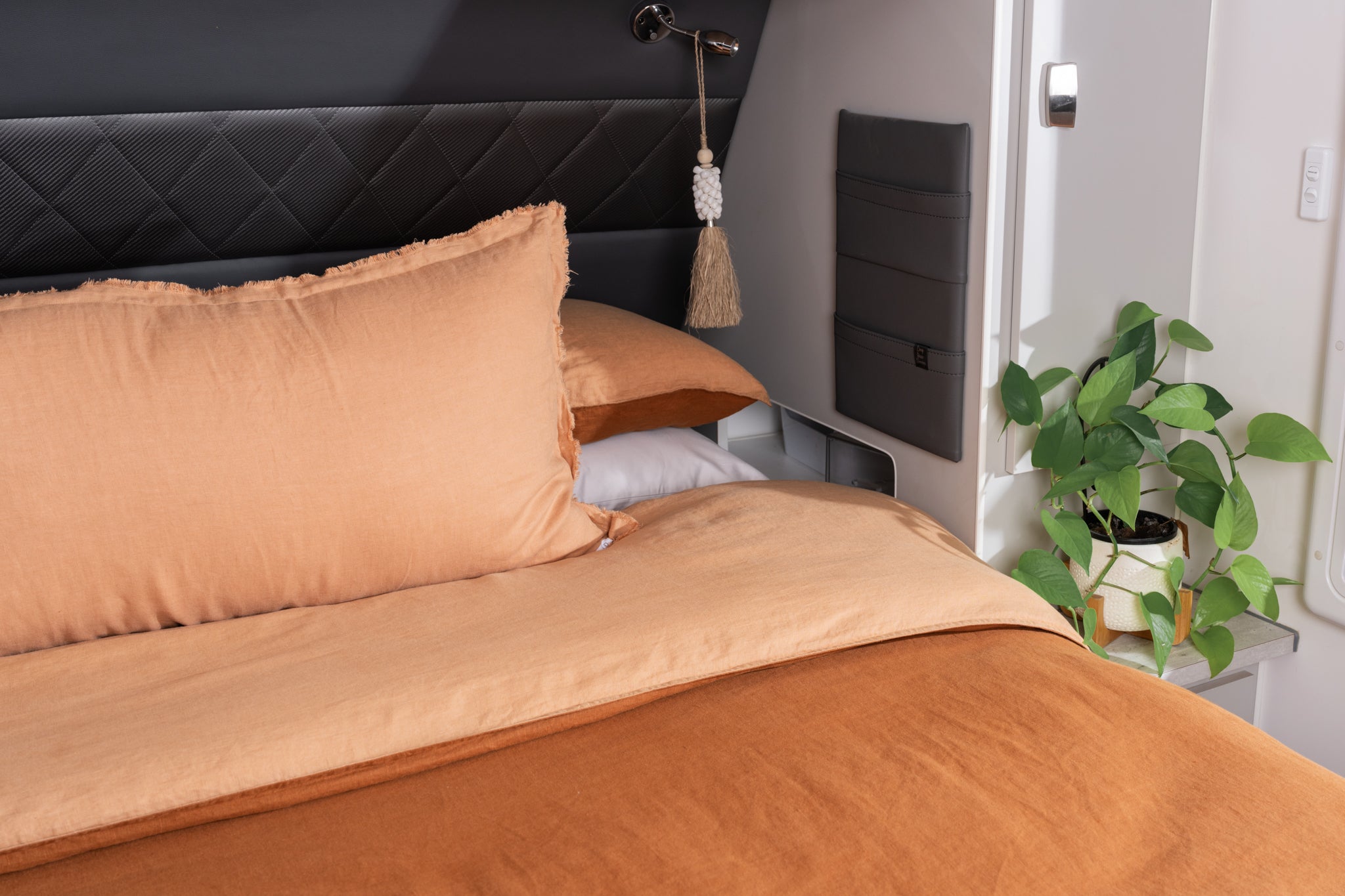 A quilt cover in peach and rust displayed on a caravan bed
